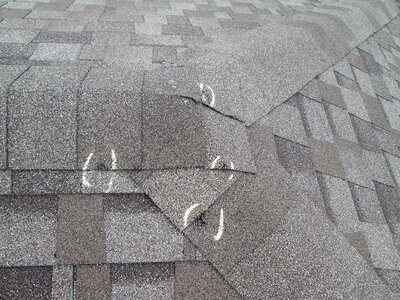 Four hail damage spots on a asphalt shingle roof identified with chalk marks