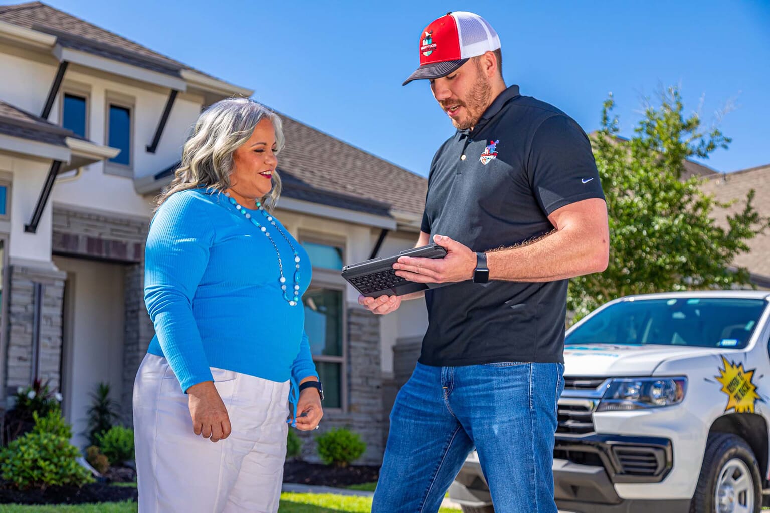A Mighty Dog Roofing solar contractor discussing project details with his customer outside her home